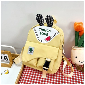 Detail of yellow school backpack with checkered ears and cartoon watermelon prints