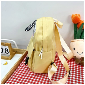 Detail view of yellow cartoon schoolbag with adjustable straps and side checkered ear design