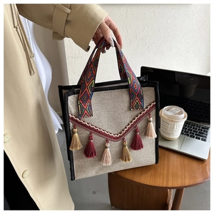 Détail du sac seau en lin avec poignée tissée colorée et gland à franges sur un bureau