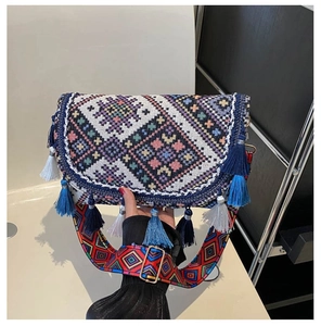 Close-up of bohemian crossbody bag with colorful geometric jacquard and blue fringe trim
