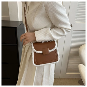 Detailed view of brown leather crossbody bag featuring soft white faux fur trim and accents