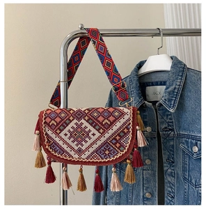 Detail of bohemian crossbody bag with intricate ethnic weaving and colorful tassels