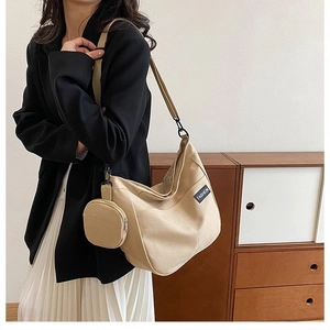 Detail view of beige large canvas tote bag with small detachable round coin purse charm