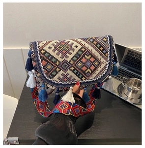 Detail of hand-woven ethnic crossbody bag with geometric embroidery and blue tassels