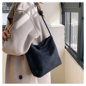 Dettaglio della borsa tote in pelle scamosciata nera con testo e spalline annodate