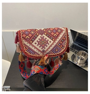 Close-up of ethnic woven crossbody bag with colorful tassels and embroidered strap