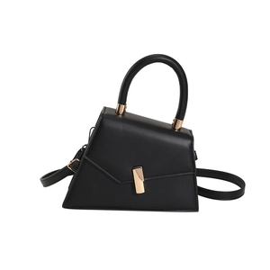 Minimalist black matte leather trapezoid handbag with gold buckle and adjustable strap