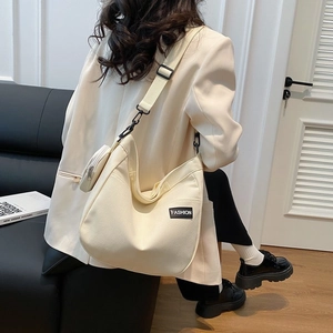 Large beige canvas tote bag shown as a shoulder bag with small coin purse detail