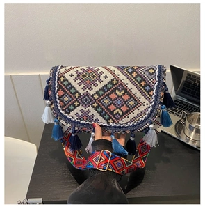 Detailed close-up of bohemian woven crossbody bag with colorful geometric patterns and long tassels