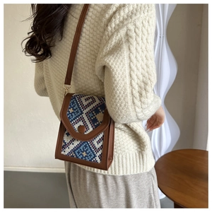 Close-up of vintage geometric pattern cross-body bag with leather trim on model