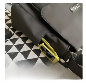 Dettaglio della borsa a tracolla in tela nera con tasca laterale e ricamo bianco