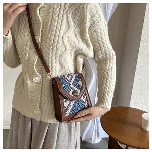 Detailed close-up of bohemian woven phone bag with geometric pattern and brown strap