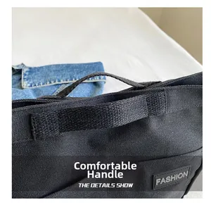 Detail of comfortable handle on black canvas tote bag with fashion label accent
