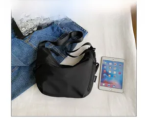 Vue détaillée du sac bandoulière croissant noir en nylon mat avec étiquette tendance
