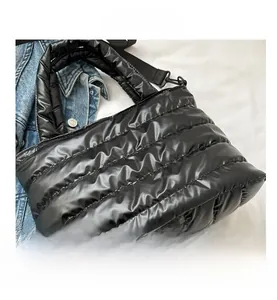 Macro shot of black glossy quilted nylon bag showing padded texture and handle detail