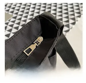 Dettaglio della cerniera in metallo dorato e del tessuto in nylon nero sulla borsa a tracolla