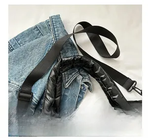 Detail of black quilted puffer bag showing thick padded handle and wide nylon strap