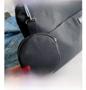 Detail view of black canvas tote bag featuring a detachable round coin purse and zipper
