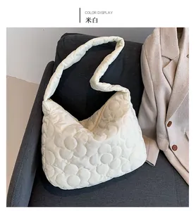 Detail view of off-white quilted puffer tote bag with floral cloud pattern on a sofa