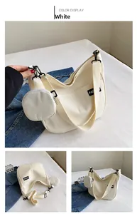 Detail of off-white canvas hobo bag with wide shoulder strap and round coin purse attachment