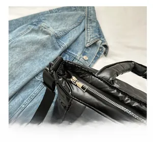 Close-up of smooth silver zipper on black quilted puffer shoulder bag for women