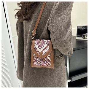 Close-up of geometric ethnic pattern crossbody phone bag with brown leather trim details