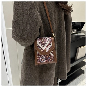 Close-up of vintage geometric pattern woven crossbody phone bag with leather trim detail