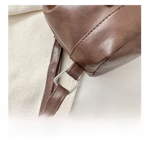 Macro shot of silver metal buckle connecting the brown leather strap and bag body