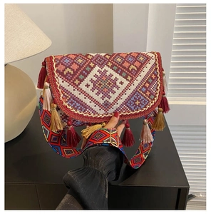 Detailed macro view of bohemian embroidery pattern and colorful tassels on crossbody bag