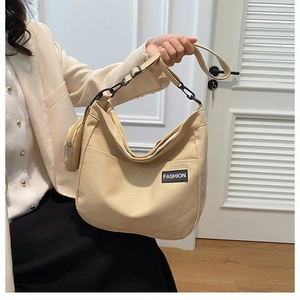 Detail of beige canvas tote bag showing fashion patch and mini round coin purse attachment