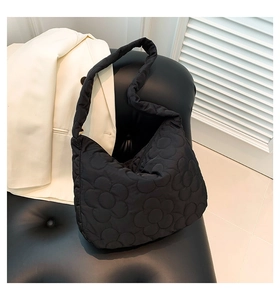 Detail of black puffer tote bag showing floral quilted nylon and soft padded texture