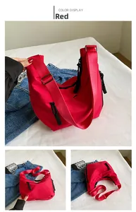Détail du sac bandoulière en nylon rouge avec fermeture éclair noire et sangle