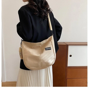Detail of khaki canvas tote with adjustable strap and small round coin purse shown on model
