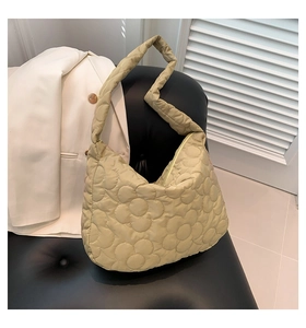 Detailed close-up of light olive green quilted tote bag with floral pattern on leather chair