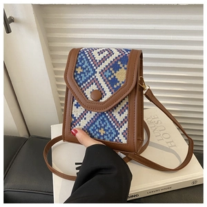 Detail view of ethnic woven crossbody phone bag with geometric pattern and brown leather trim