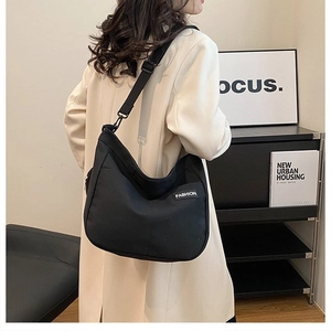 Close-up of black canvas tote bag with adjustable strap and white fashion label detail