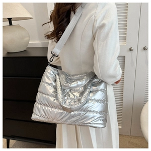 Detail of silver metallic quilted crossbody bag with stylish wide shoulder strap on model