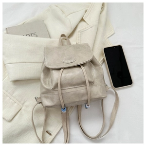 Detail view of cream mini backpack with textured label, drawstring and bead closure