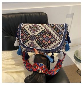 Close-up of bohemian woven crossbody bag with colorful patterns and tassels on wide strap