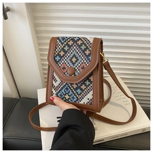 Close-up of vintage ethnic woven pattern and brown faux leather on a small crossbody phone bag