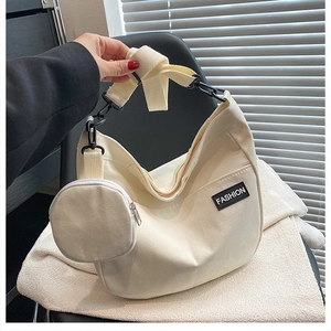 Detail of off-white crescent canvas tote bag featuring adjustable strap and fashion label