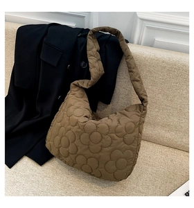Detail of a brown quilted tote bag with floral patterns on a stylish beige sofa