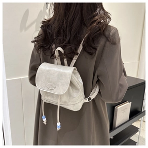 Detailed shot of beige faux leather mini backpack with Fashion logo and drawstring bead