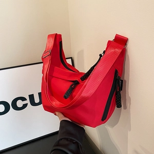 Détail d'un sac bandoulière rouge en forme de croissant avec fermeture éclair noire