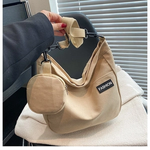 Close-up of beige canvas tote with detachable round purse and black metal hardware hook