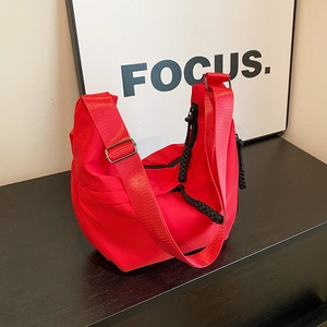 Détail du sac demi-lune en nylon rouge avec fermeture éclair noire et bandoulière réglable