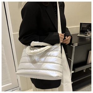 Close-up of white quilted puffer tote bag with padded texture and crossbody strap detail