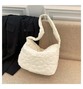 Detail view of cream white quilted puffer tote bag with floral pattern and nylon texture