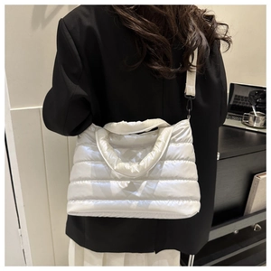 Close-up of a white quilted crossbody bag with soft padded texture and crossbody strap