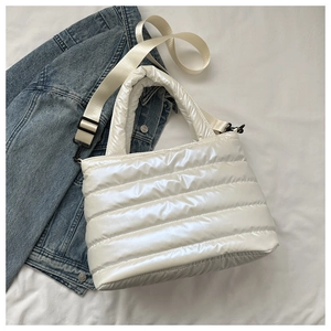 Close-up of white quilted puffer bag with glossy nylon texture and adjustable strap